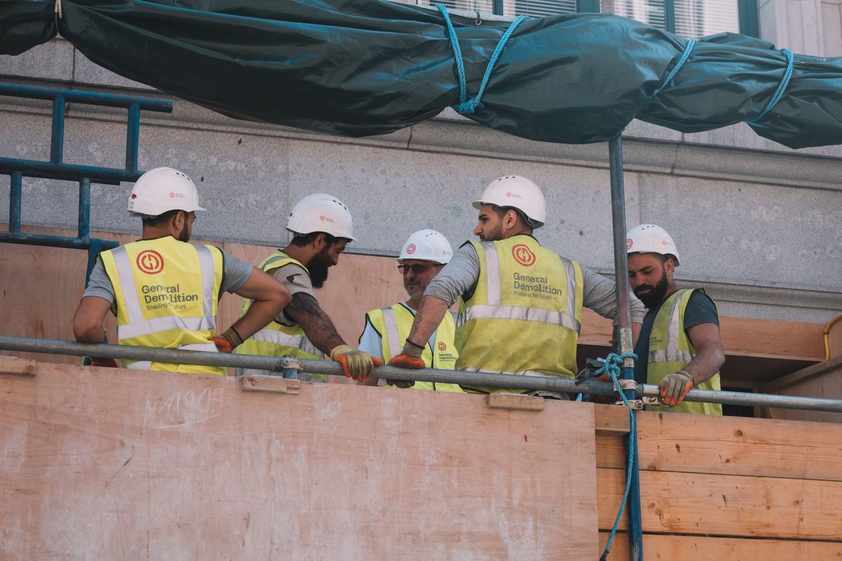 A crew in helmets and vests on the scaffolding of a building site
