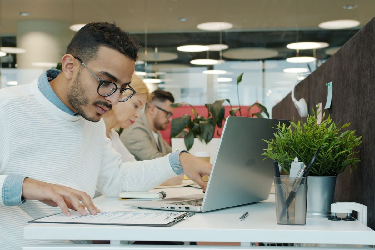 An employee works on a laptop in an open-plan office