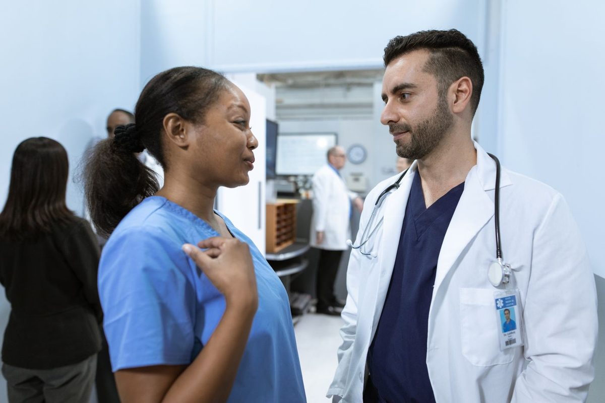 Uma enfermeira e um médico conversam no corredor do hospital