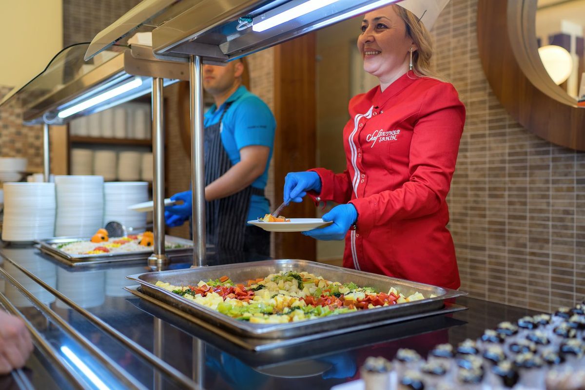 Cafeteria staff serving food at the line counter
