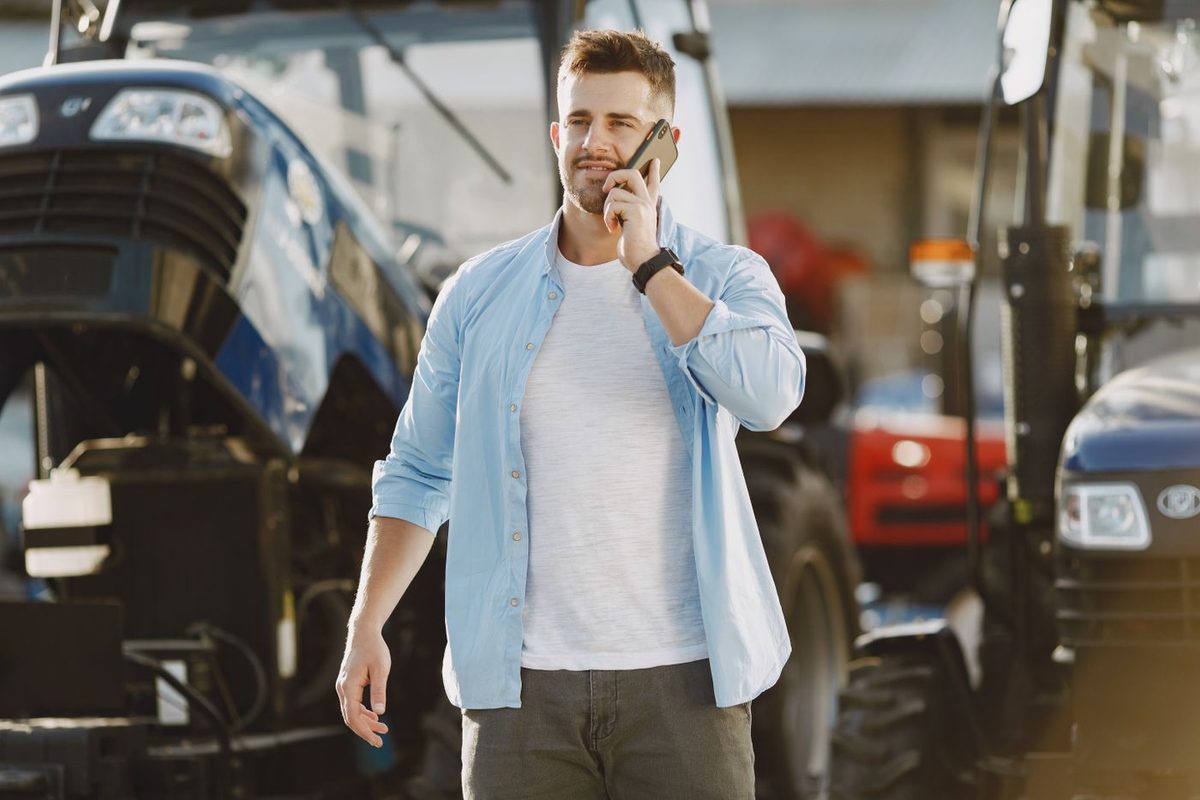 A supervisor on the phone in front of machinery in a work yard